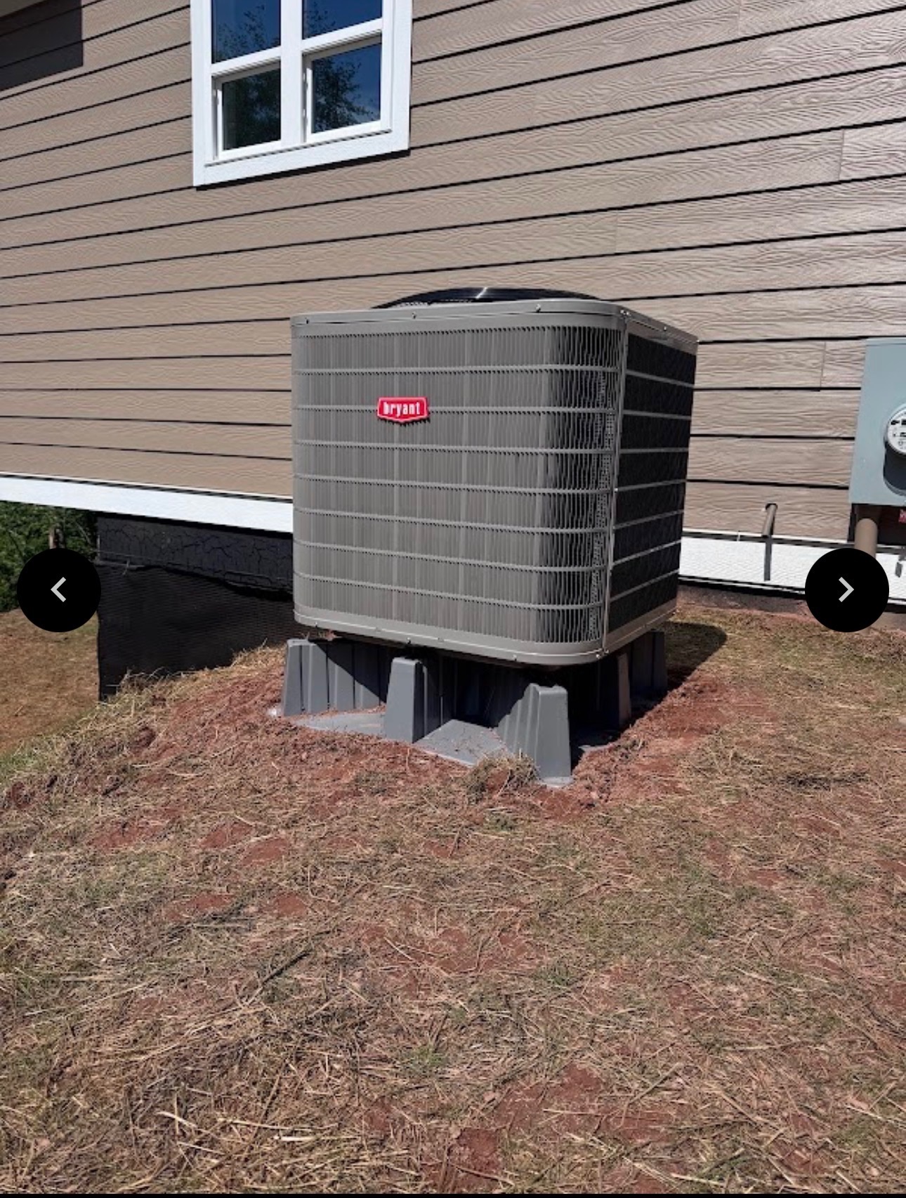 Bryant HVAC unit on a concrete pad next to a tan-sided house
